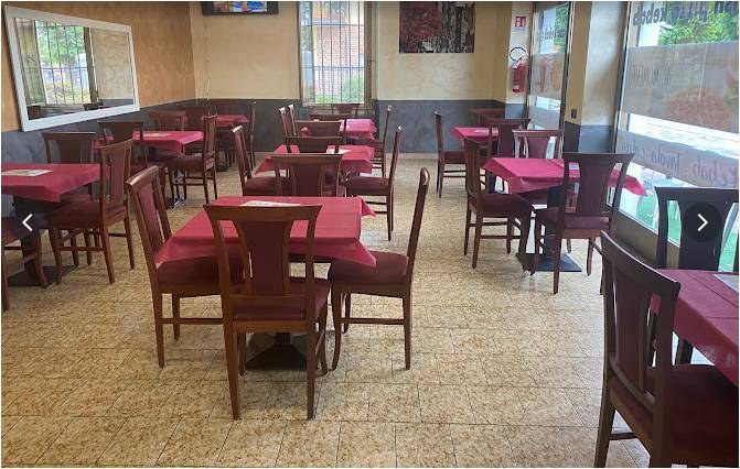 Sala interna con tavoli apparecchiati del locale di pizza e kebab a Rovato