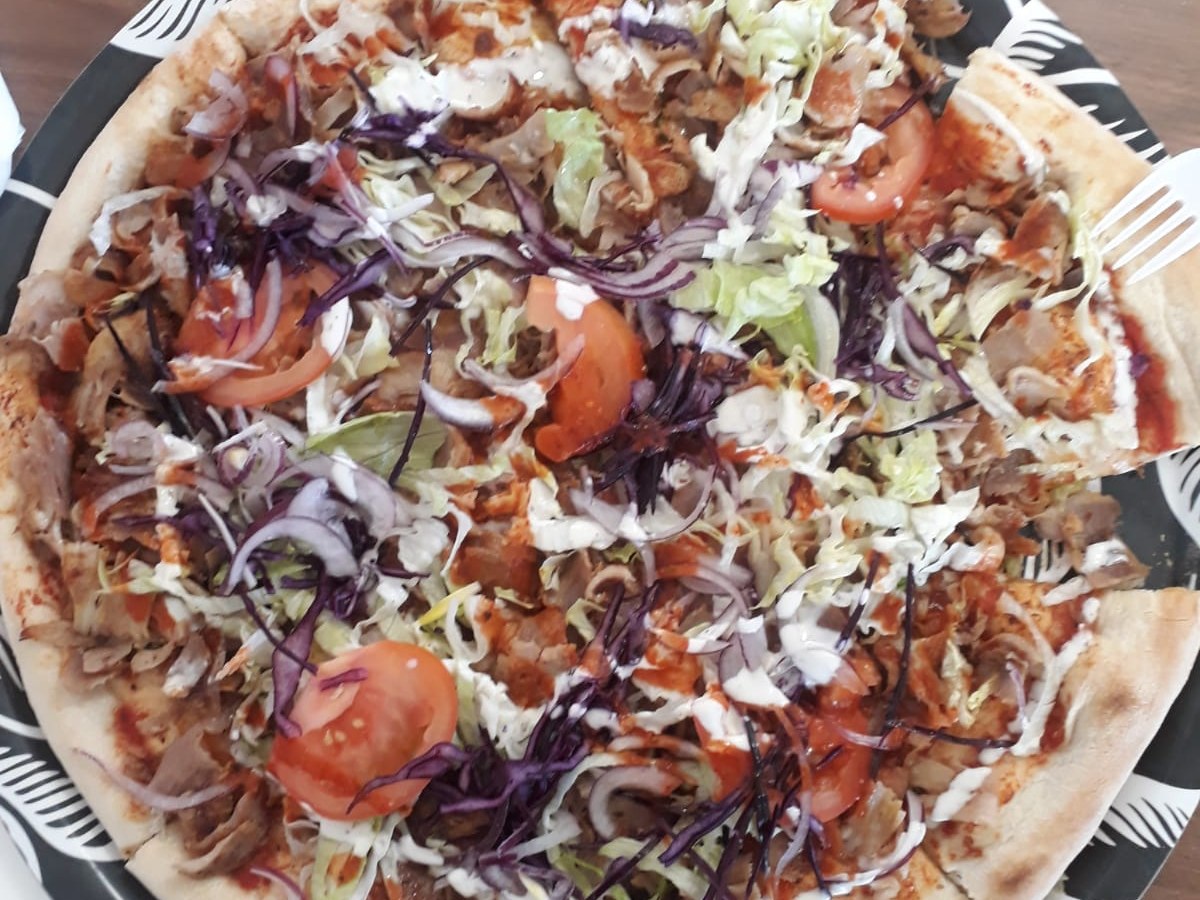 Pizza farcita con carne di kebab, insalata e pomodoro servita nel locale di pizza e kebab a Rovato